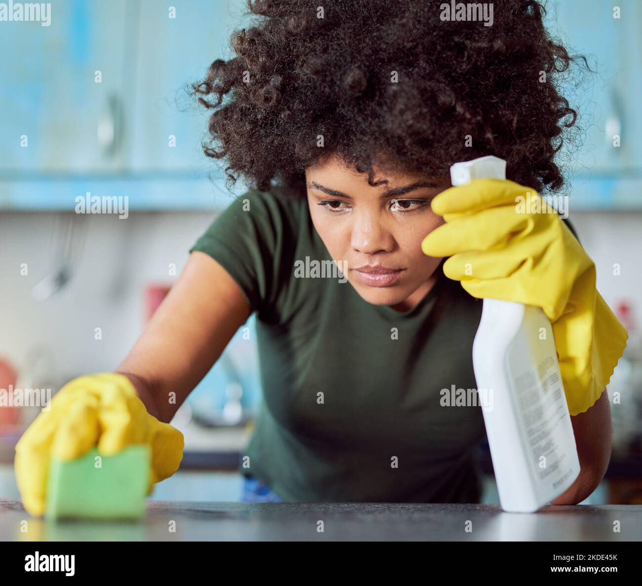 Eine attraktive junge Frau mit gelben Handschuhen, die ihr Zuhause putzt. Stockfoto