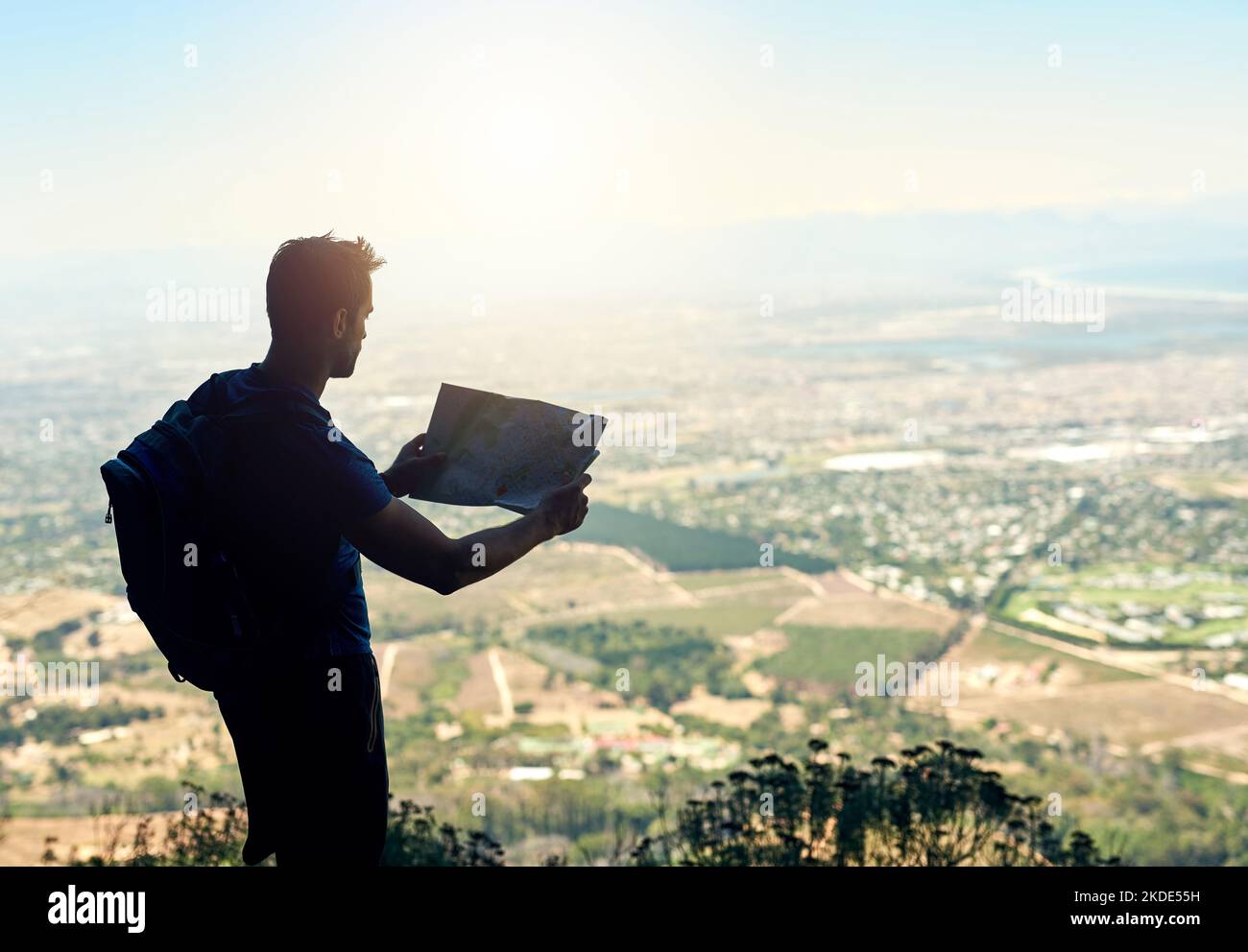 Weiter so, weiter so. Rückansicht eines jungen Mannes, der eine Karte las, während er auf einem Berg stand. Stockfoto
