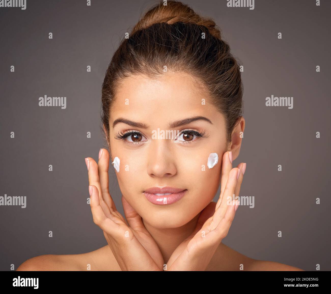 Tun Sie Ihrer Haut einen Gefallen. Porträt eines jungen Models, das im Studio Feuchtigkeitscreme auf ihr Gesicht anwendet. Stockfoto