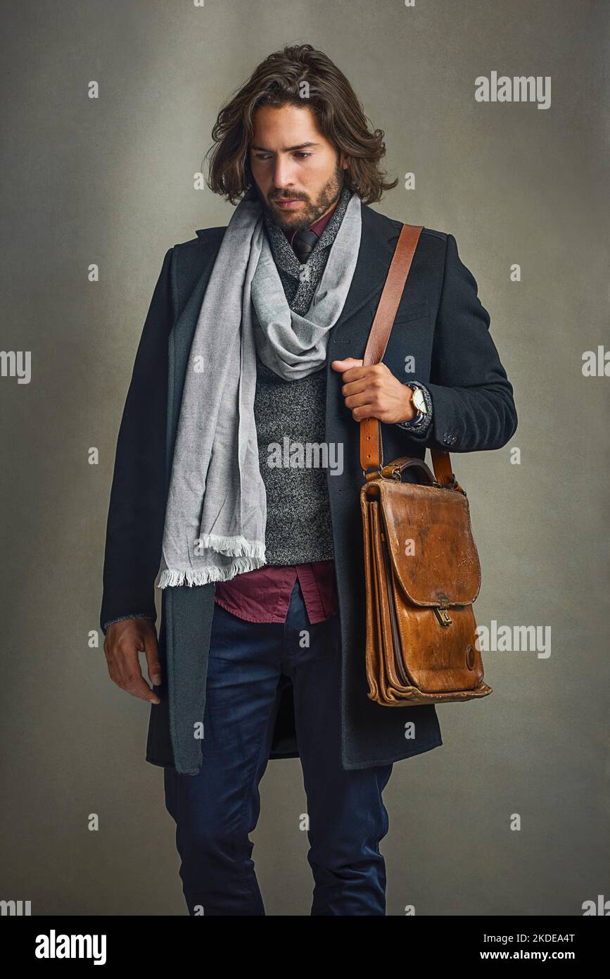 Die Leute werden starren, also lohnt es sich. Ein stilvoll gekleideter Mann posiert mit einer Ledertasche im Studio. Stockfoto