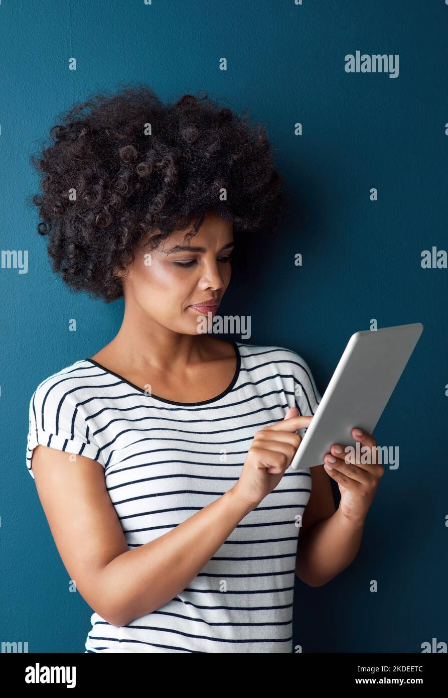 Die digitale Domäne ist meine Welt. Studioaufnahme einer attraktiven jungen Frau mit einem digitalen Tablet vor blauem Hintergrund. Stockfoto