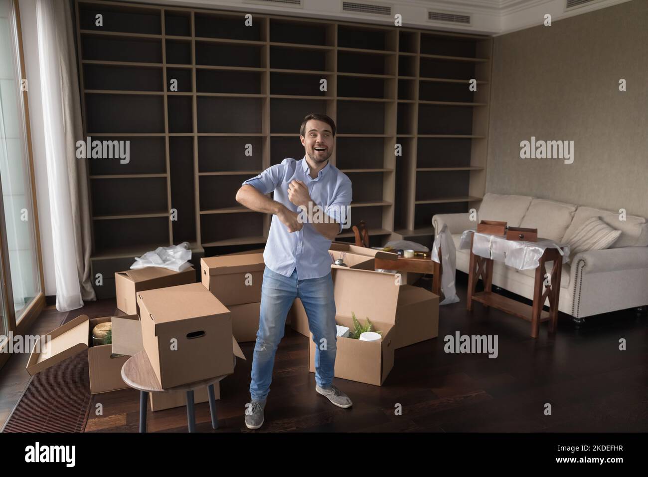Mann, der im Wohnzimmer voller Boxen tanzt, feiert Umzug Stockfoto
