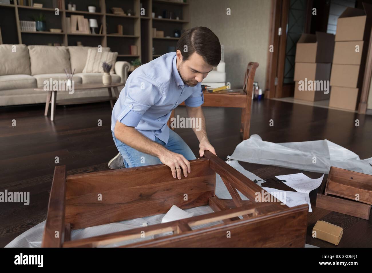 Junger Mann, der zu Hause Holzmöbel zusammengebaut hat Stockfoto
