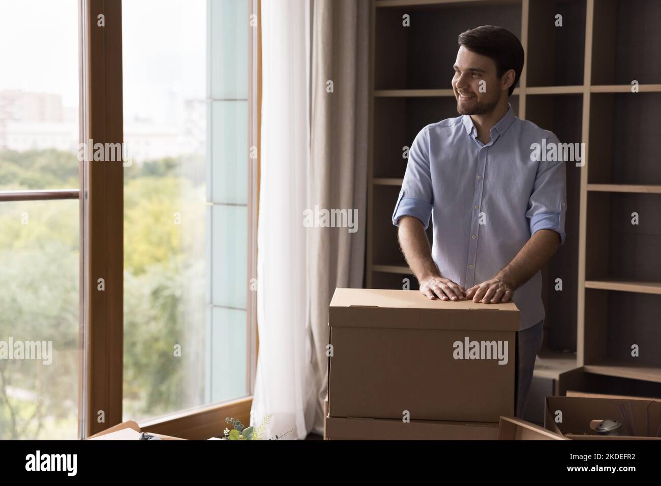 Der Mann posiert drinnen mit Haufen verpackter Gegenstände in Schachteln Stockfoto