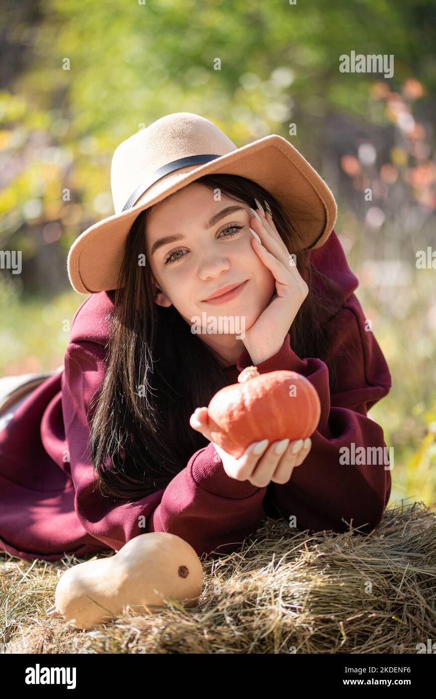 Kaukasische Teenager-Mädchen sitzt im Herbst Park. Sie hält orangen Kürbis in den Händen. Herbstsaison Stockfoto