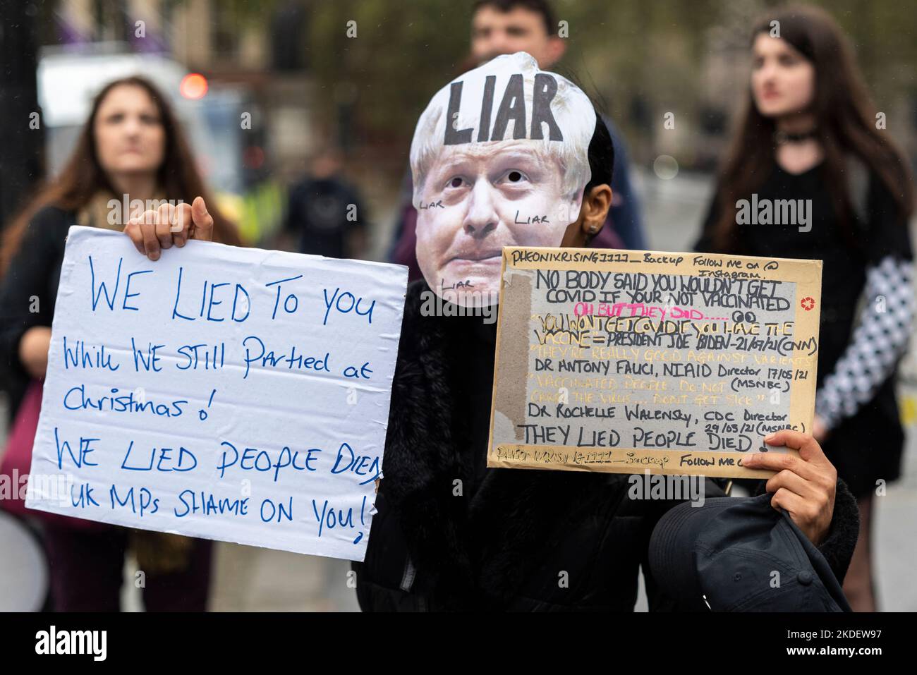 Protestierender bei einem Protest in London gegen die konservative Regierung. Boris Johnson Maske mit Lügner und Covid Verschwörungstheorie Textplakate Stockfoto