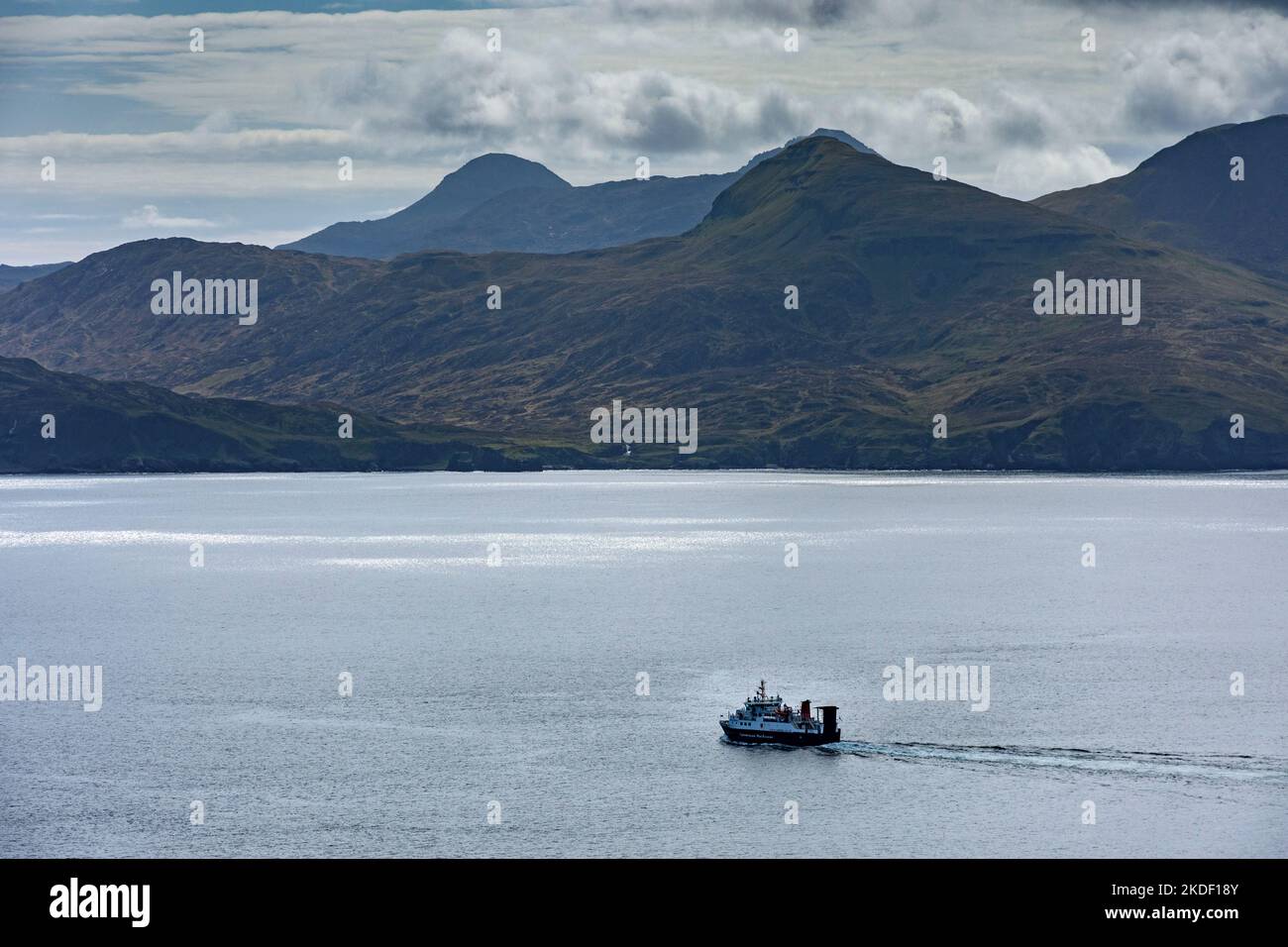 Die Caledonian MacBrayne Small Isles Fähre, die MV Lochnevis, verlässt den Hafen, Isle of Canna, Schottland, VEREINIGTES KÖNIGREICH. Die Berge von Rum dahinter. Stockfoto
