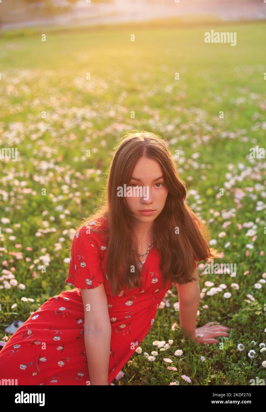 Junge schöne gir in rotem Kleid isl ruht auf frischem Frühlingsgras Stockfoto