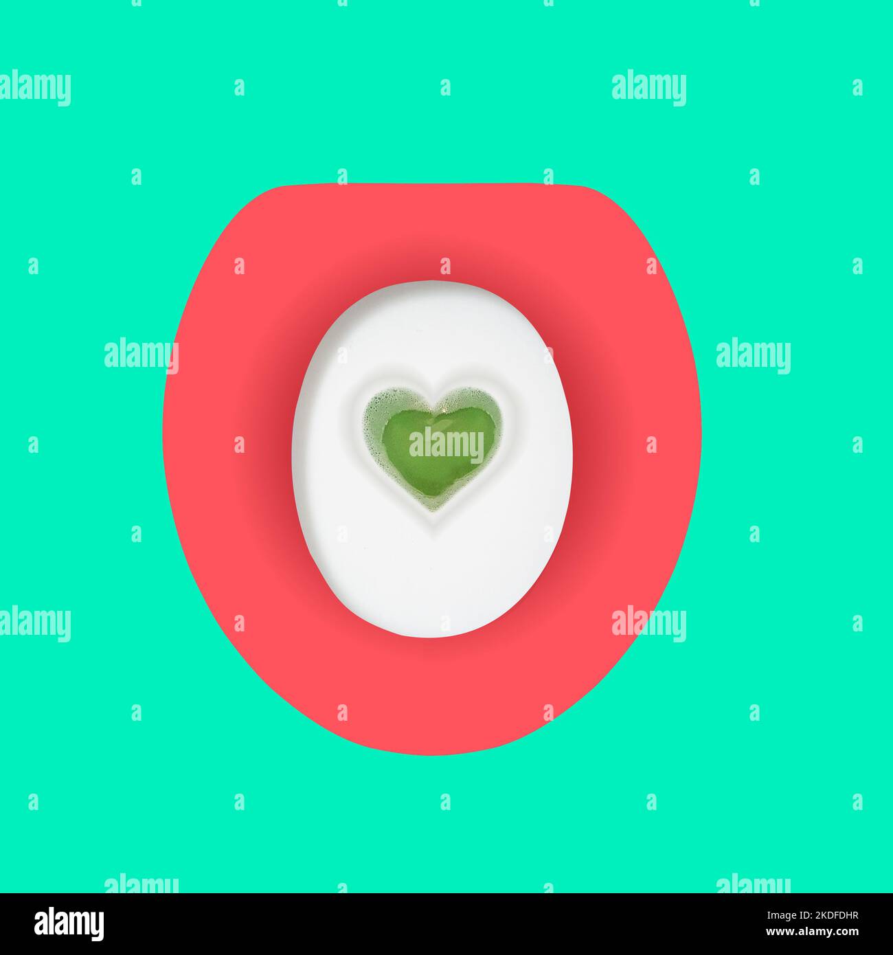 Rote Toilettenschüssel mit herzförmigem Abfluss und grünem pastellfarbenem Hintergrund. Konzeptuelle Liebe verletzt die Idee eines Banners. Stockfoto