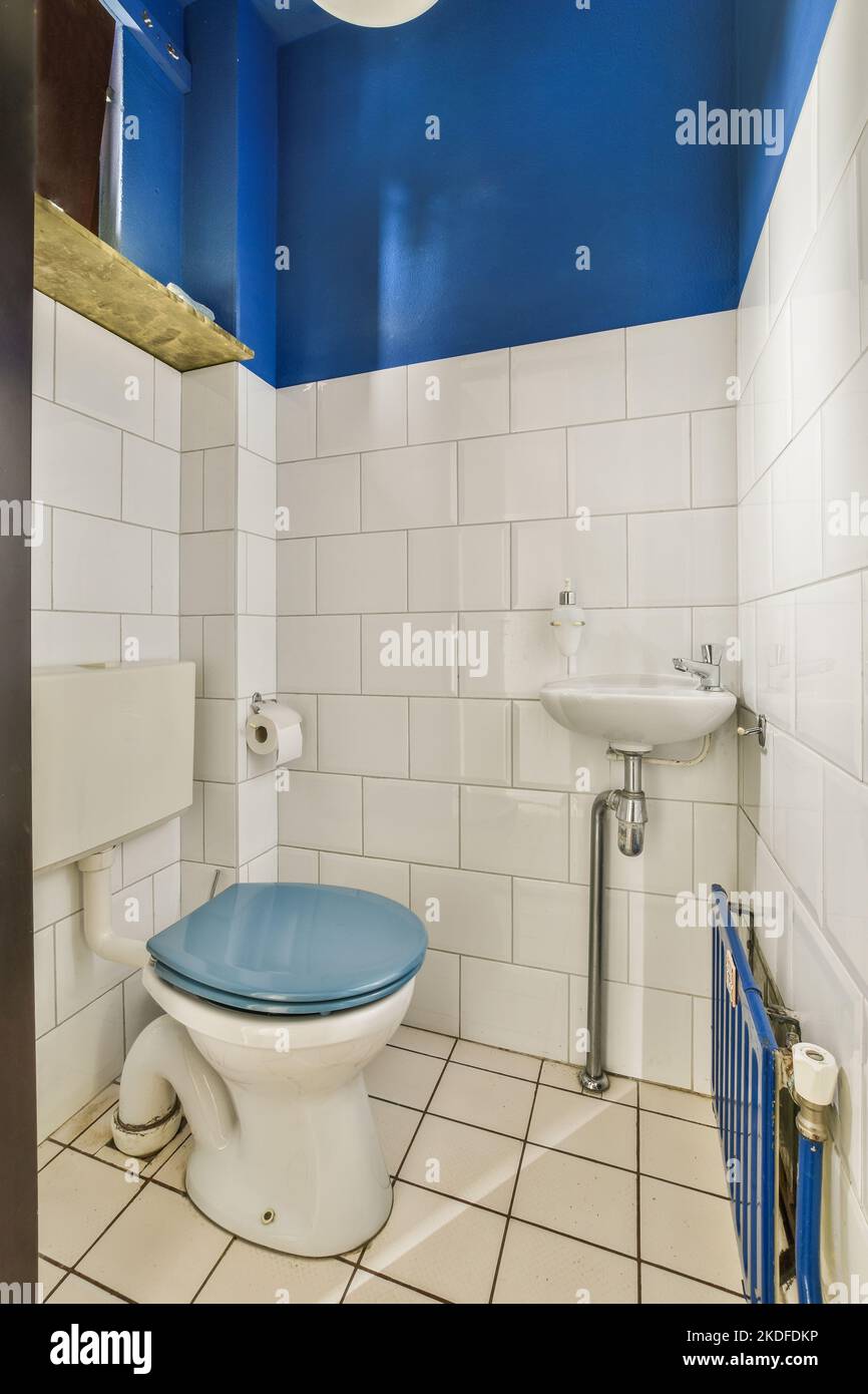 Die Toilette befindet sich zwischen dem Waschbecken im kleinen gefliesten Badezimmer eines modernen Apartments Stockfoto