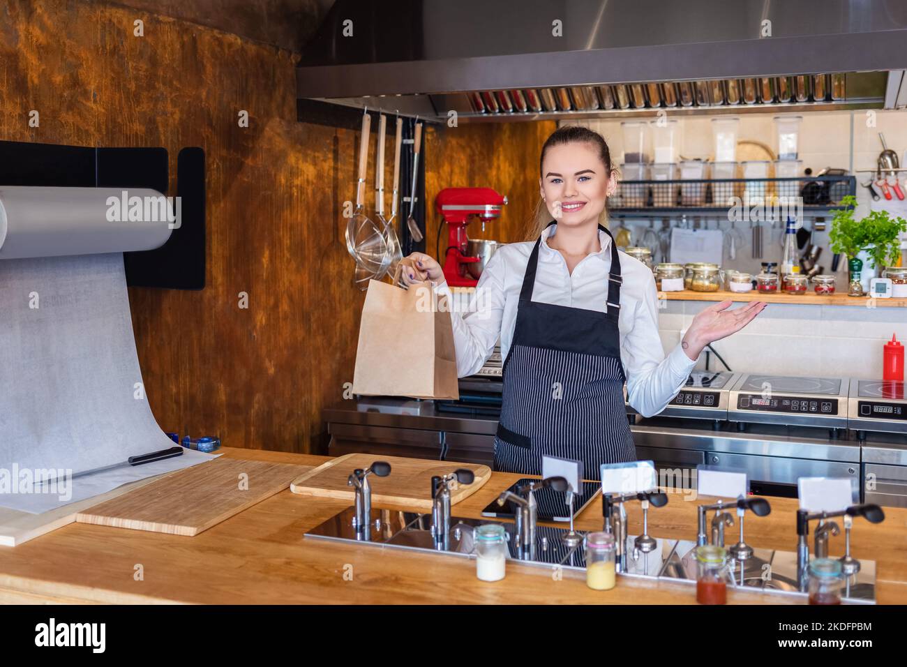 Kellnerin serviert dem Gast Essen zum Mitnehmen an der Theke in einem kleinen Familienrestaurant. Stockfoto