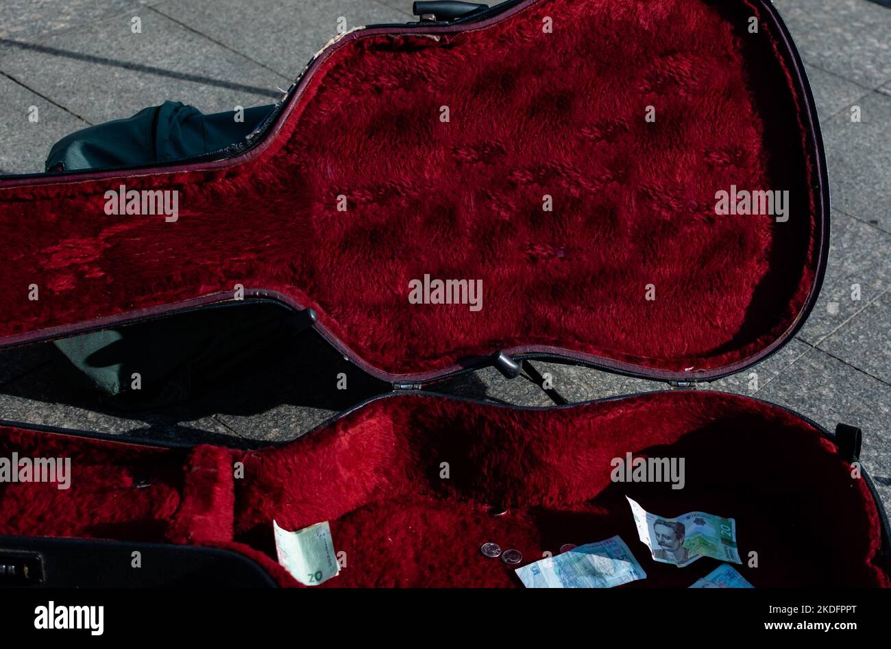 Offenes Gehäuse für akustische Gitarre auf dem Bürgersteig der Fußgängerzone mit Banknoten Stockfoto