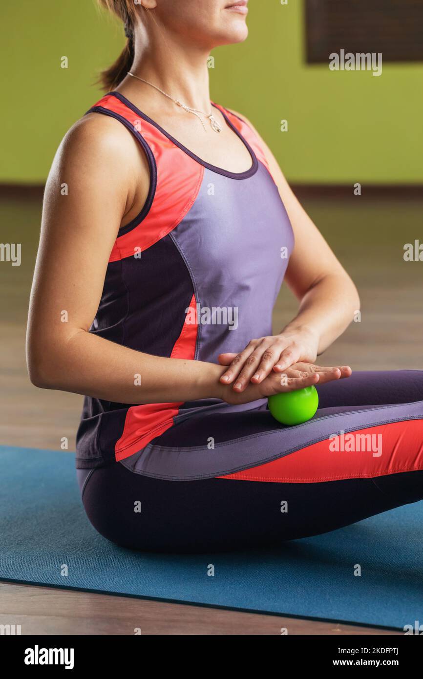 Eine junge Frau massiert die Oberschenkelmuskulatur mit einem Massageball Stockfoto