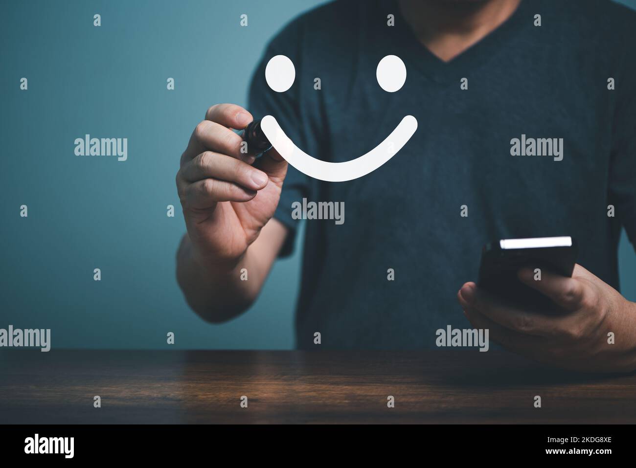 Hand des Kunden zeigen ein Feedback mit Zufriedenheit lächelndes Gesichtsschild und halten Handy mit blauem Hintergrund. Service-Rating, Feedback-Konzept. Stockfoto