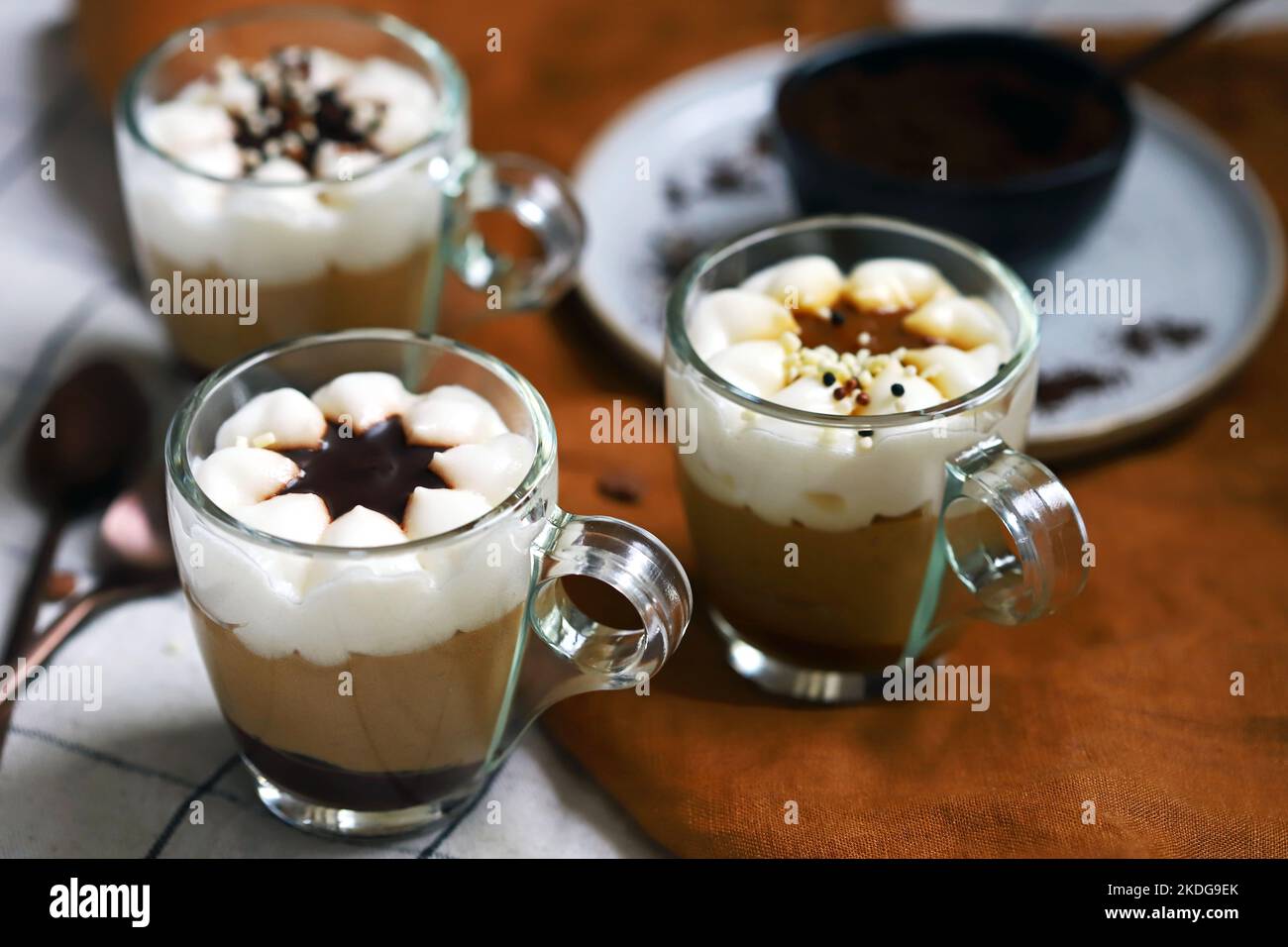 Kleine Tassen mit einem dreischichtigen Kaffee-Karamell-Dessert. Köstlicher Pudding in Glasbechern. Stockfoto