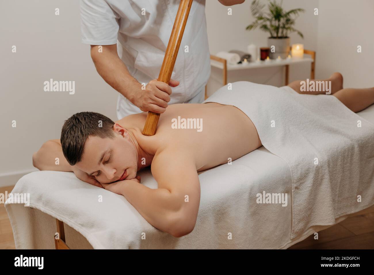 Männerrücken während der traditionellen thai-Massage mit Stick. Orientalische Alternativmedizin mit Holzwerkzeugen. Körperpflege und SPA in Thailand Resort. Stockfoto