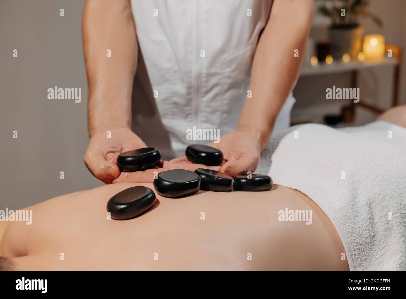 Der Rücken des Mannes bei der Massage mit heißen Steinen. Körperpflege und SPA im Resort. Stockfoto