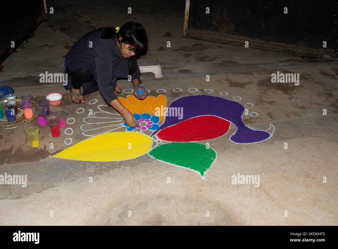 Stammesvolk, das am Vorabend von Diwali Rrangoli zieht Stockfoto