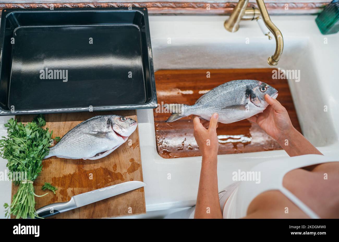 Frische orata oder dorada Fisch Reinigung nach dem Ausschneiden unter dem Spülbecken Wasserhahn. Backblech zum Kochen vorbereitet. Gesunde, frische Meeresfrüchte bereiten vor Stockfoto