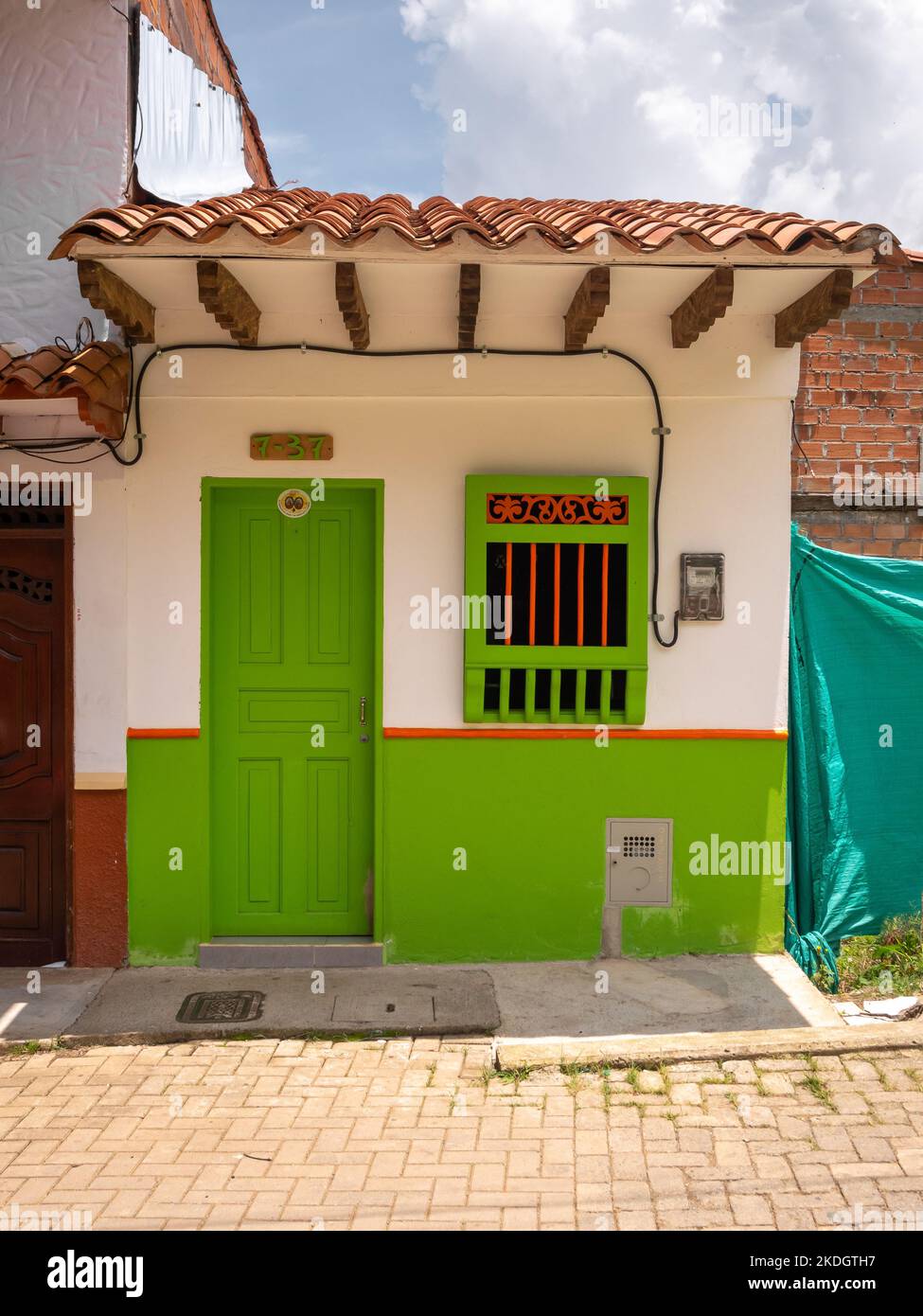 Jerico, Antioquia, Kolumbien - April 5 2022: Weißes, winziges Haus im Kolonialstil mit grün lackierten Holztüren und Fenstern Stockfoto