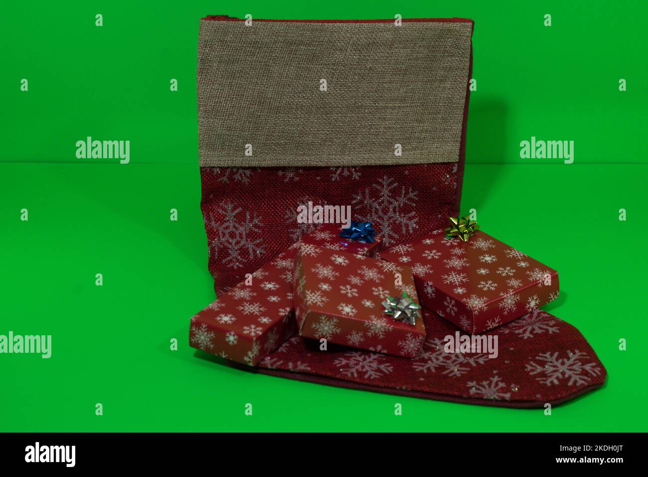 Weihnachtsstrumpf gefüllt mit Geschenken auf grünem Hintergrund! Stockfoto