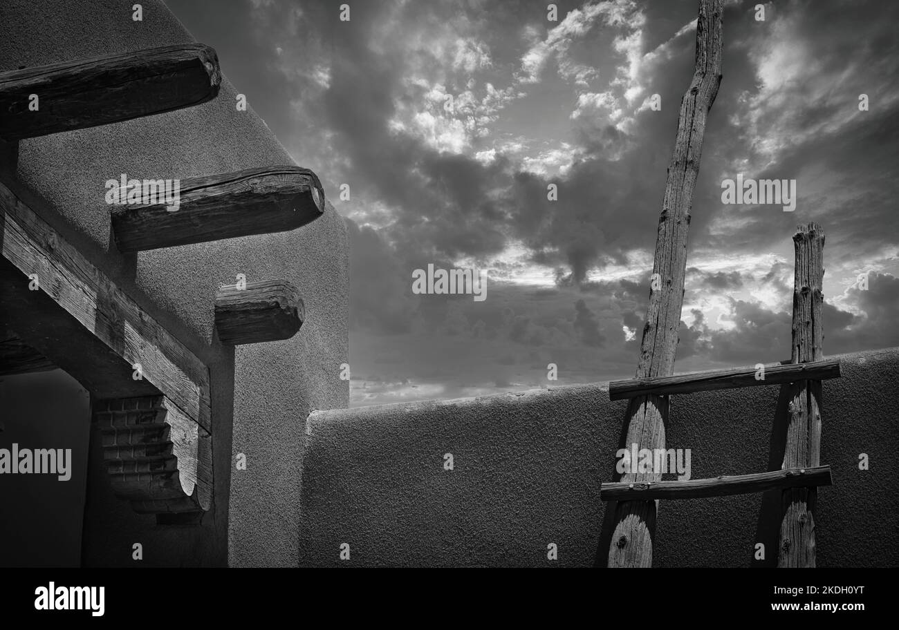 Traditionelle Holzleiter auf Adobe südwestlichen Architektur mit Nachmittagsregen zieht ein. Stockfoto