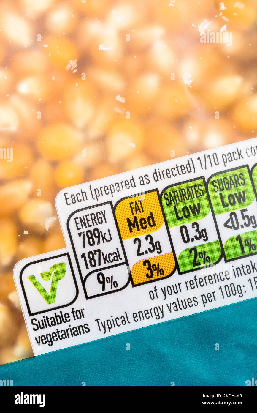 Plastikpaket von ASDA Supermarkt eigenen Etikett gelben Popcornkörnern mit Lebensmitteln Ampel. Logo für vegane Lebensmittel, Ampeletikett. Stockfoto
