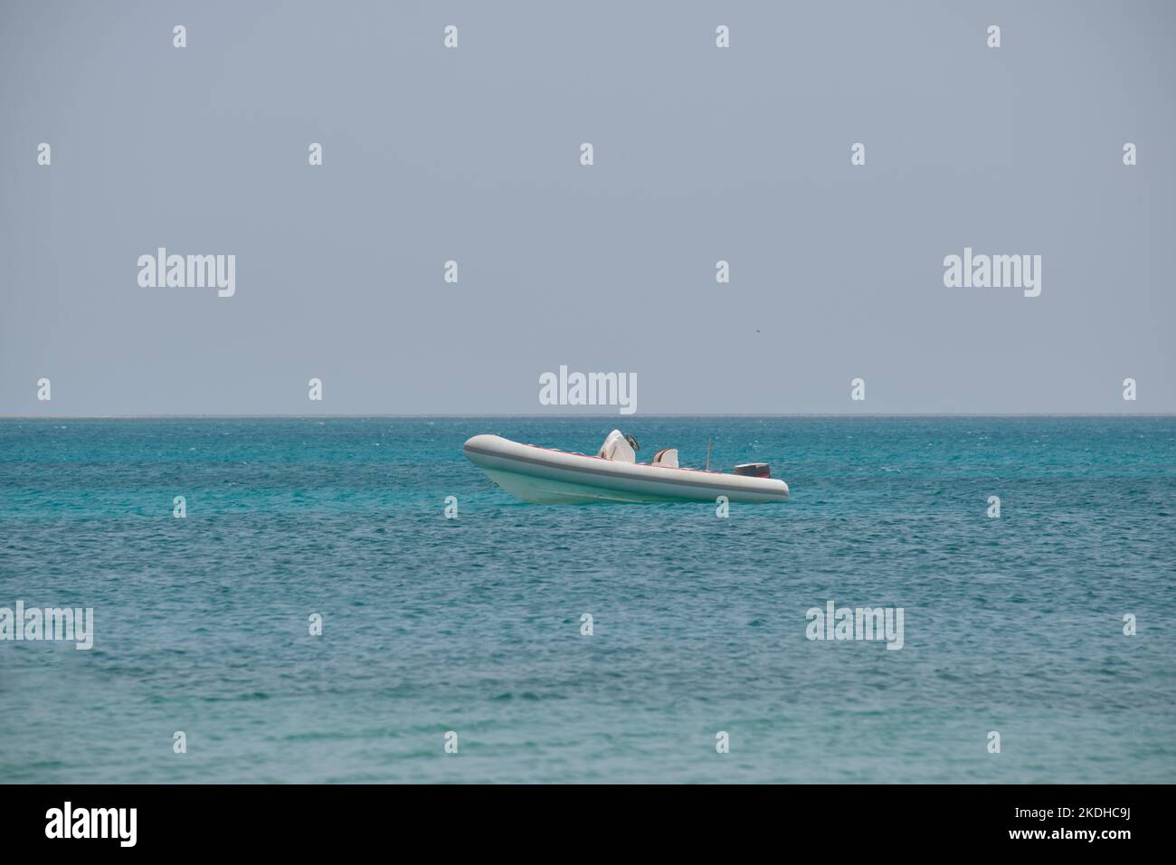 Meereslandschaft mit Wellenoberfläche aus blauem Meerwasser mit weißem Schnellboot vor Anker, das auf ruhigen Wellen schwimmt Stockfoto