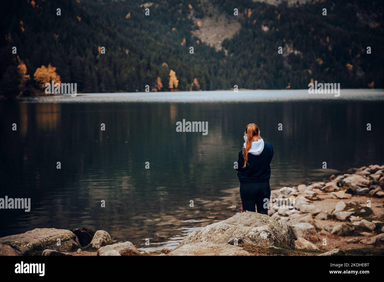 Mädchen von hinten fotografiert mit ihrem Smartphone an einem schönen See Stockfoto