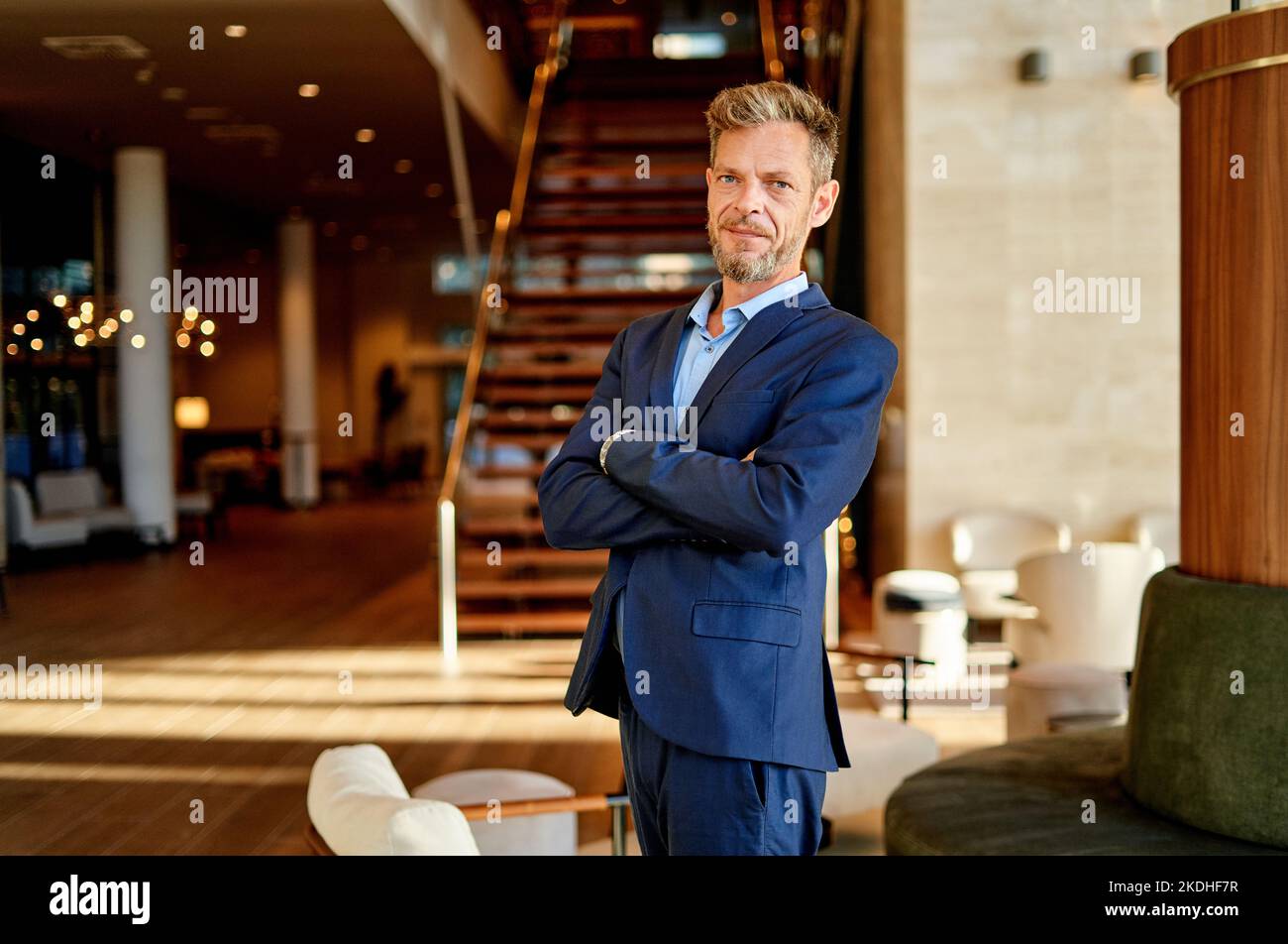 Porträt eines Geschäftsmannes mit gekreuzten Armen, der am Arbeitsplatz posiert Stockfoto
