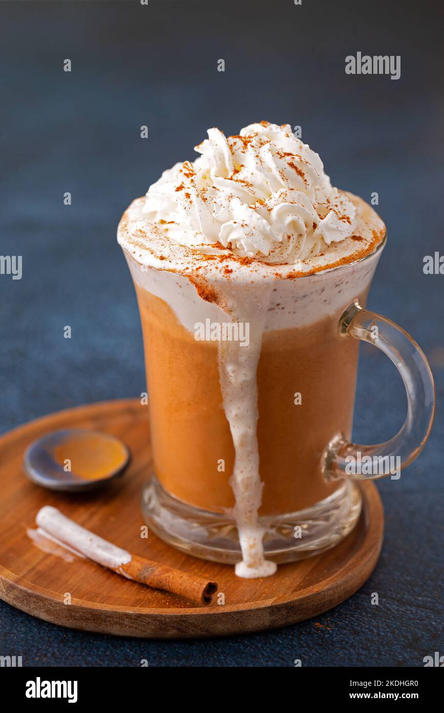 Kürbis-Gewürzkaffee Latte mit Schlagsahne und Zimt in einem Becher aus klarem Glas überfüllt; Platz zum Kopieren Stockfoto