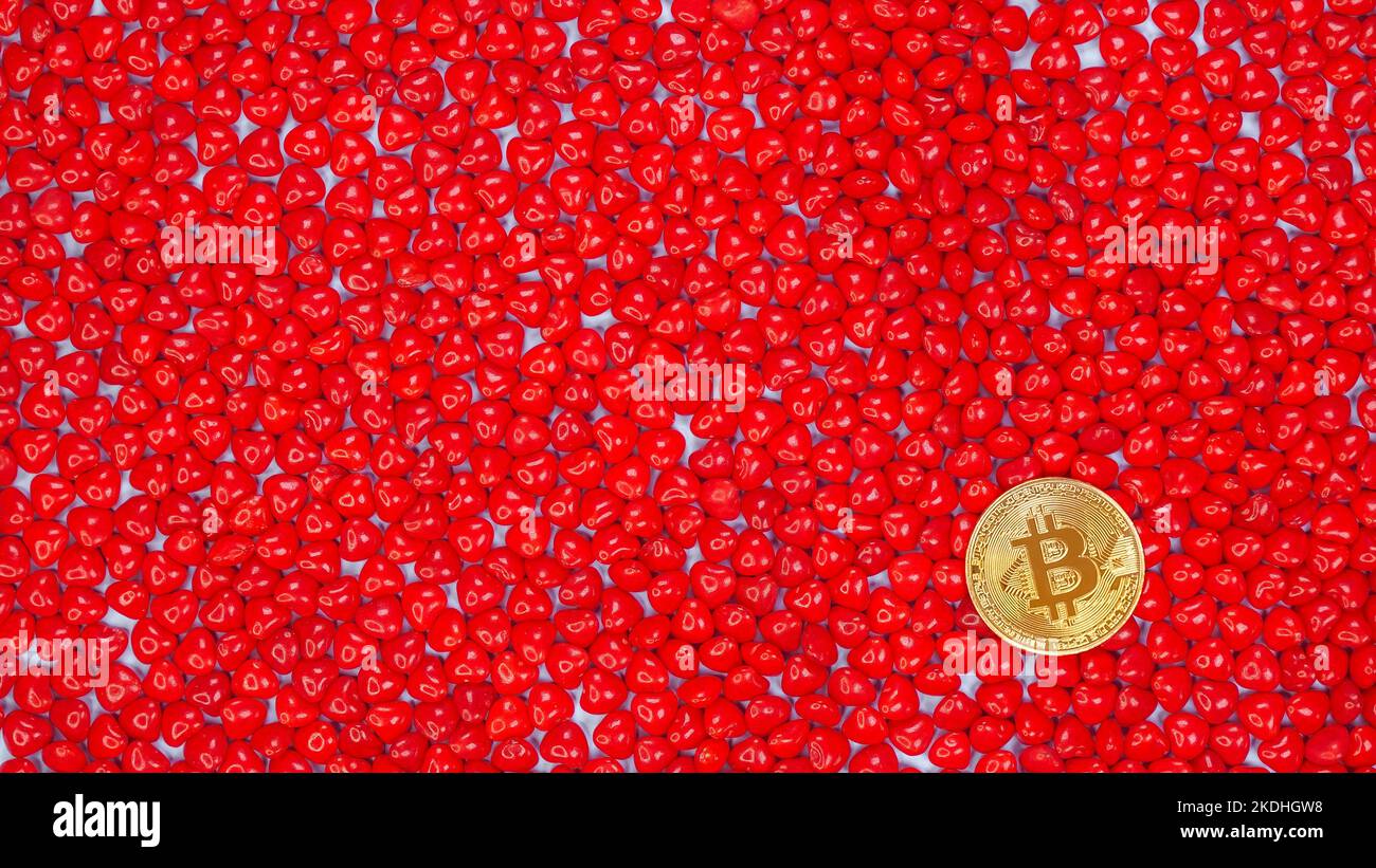 Goldene Bitcoin-Münze auf einem roten herzförmigen Bonbon-Hintergrund. Bitcoin Kryptowährung Wert Preis fallen, nach unten, rote Aktienkarte. Krypto-Währung süß Stockfoto