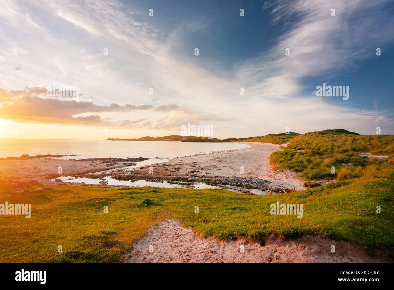 Extreme nordwestliche Spitze von Schottland. Dramatisches warmes spätes Sonnenuntergangslicht, das über dem feinen Sand und den grasbewachsenen Dünen, wispy Wolken und blauem, orangenen Himmel glüht Stockfoto