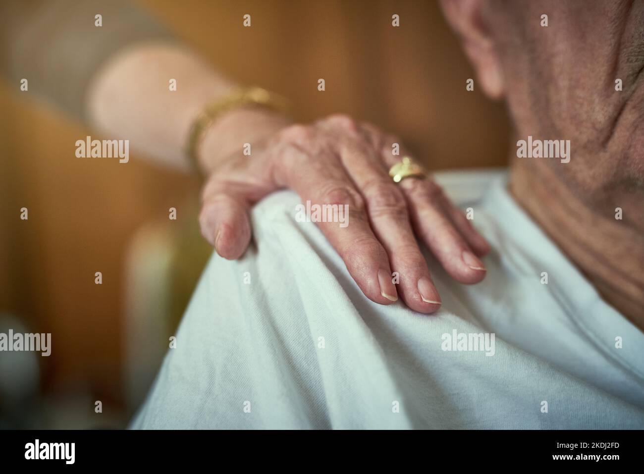 Wahre Freunde bleiben bis zum Ende bei Ihnen. Eine nicht identifizierbare ältere Frau berührt ihren Mann in einem Altersheim auf der Schulter. Stockfoto