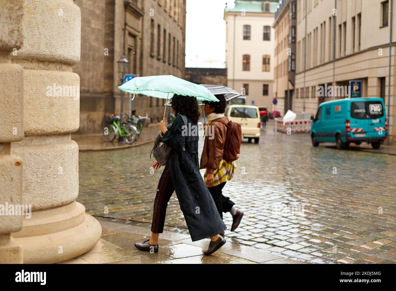 Menschen mit Sonnenschirmen laufen im Regen durch eine europäische Stadt. Dresden, Deutschland - 05.20.2019 Stockfoto