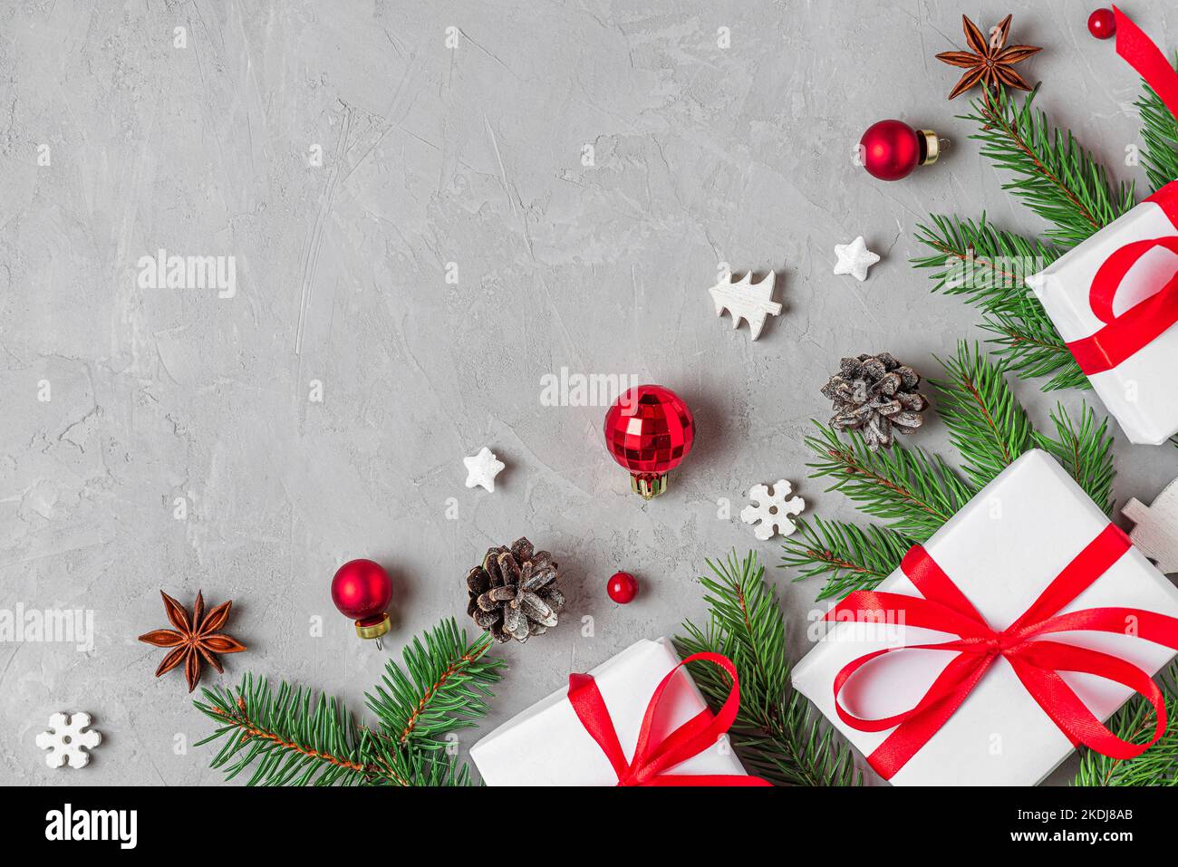 Weihnachtskomposition. Weiße Geschenkschachteln, Tannenbäume und Weihnachtsdekorationen auf grauem Hintergrund. Flach liegend. Layout. Draufsicht mit Kopierbereich Stockfoto