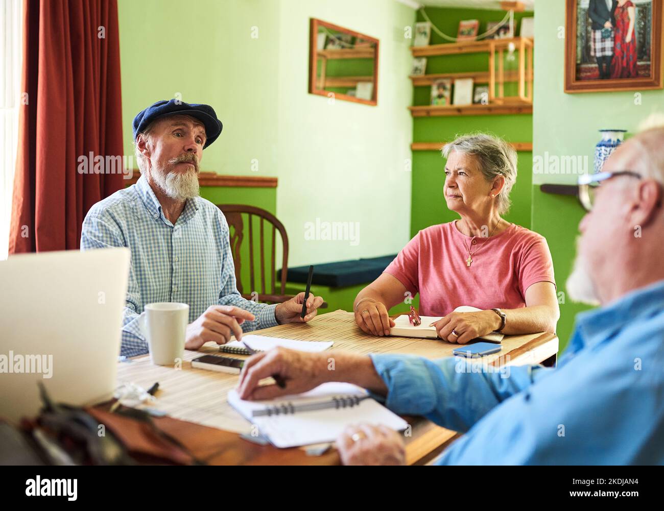 Ich bin offen für Ihre Vorschläge. Drei Senioren mit einem Treffen um einen Tisch zu Hause. Stockfoto