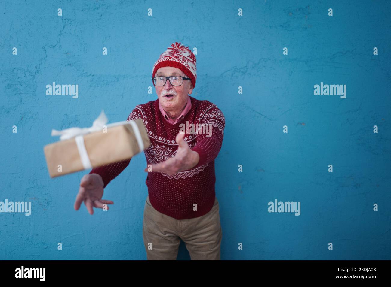 Porträt eines glücklichen älteren Mannes, der ein Geschenk anfängt, Studioaufnahmen. Stockfoto