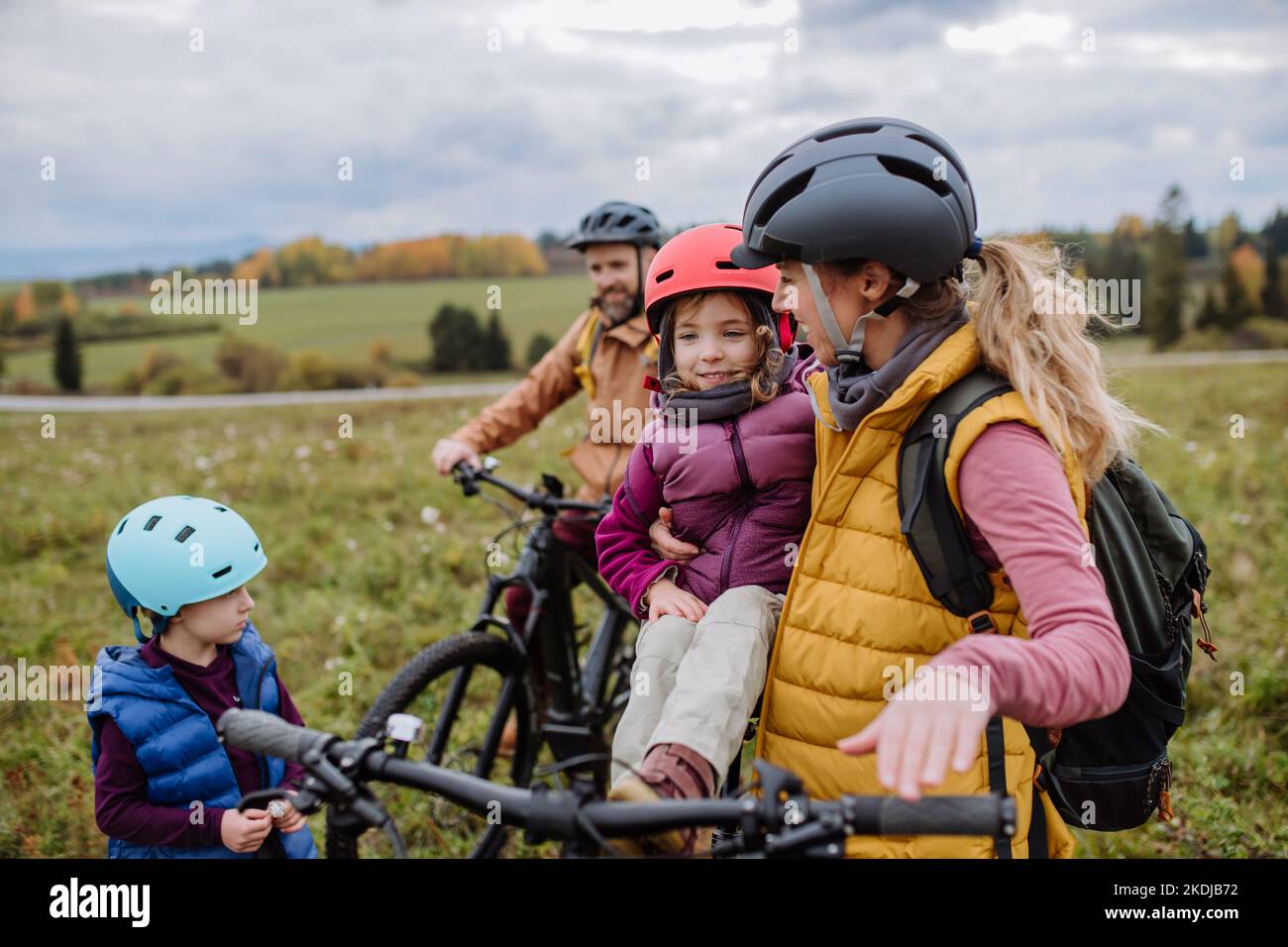Junge Familie mit kleinen Kindern, die sich auf eine Fahrradtour in der Natur vorbereiten. Gesundes Lifestyle-Konzept. Stockfoto