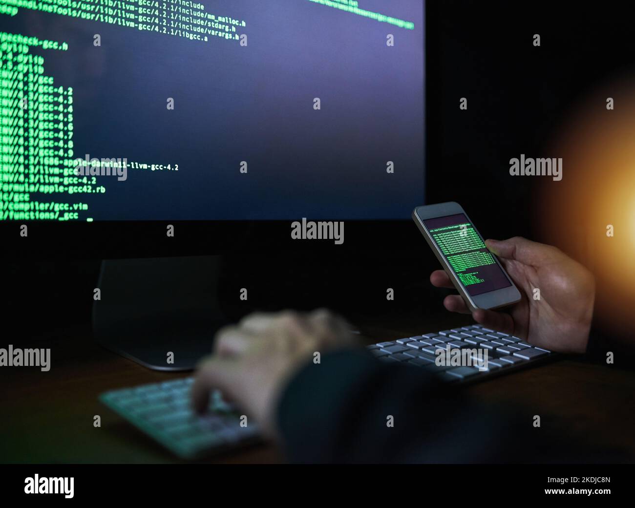 Kein Code ist uncrackable. Ein nicht identifizierbarer Computerhacker, der ein Smartphone benutzt, um nachts in ein Computernetzwerk zu hacken. Stockfoto