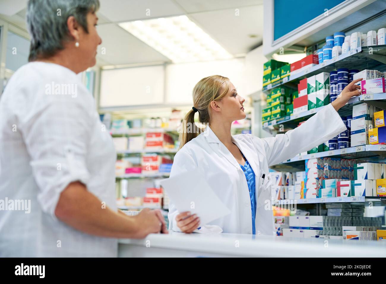 Erstklassige pharmazeutische Dienstleistung. Ein junger Apotheker, der einem Kunden hilft. Stockfoto