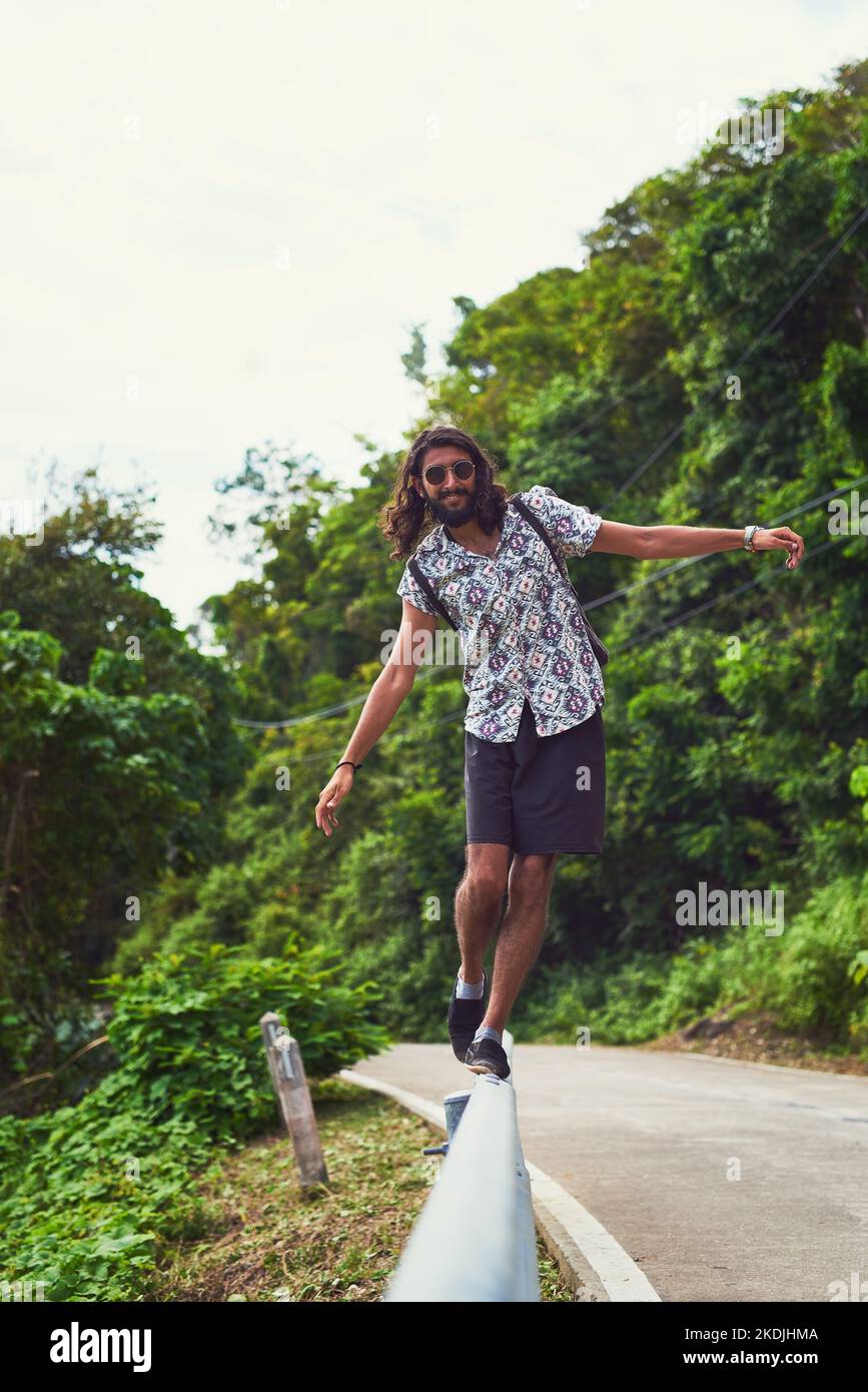 Auf der Suche nach der Straße weniger gereist. Porträt eines glücklichen jungen Mannes, der allein ein exotisches Reiseziel erkundet. Stockfoto