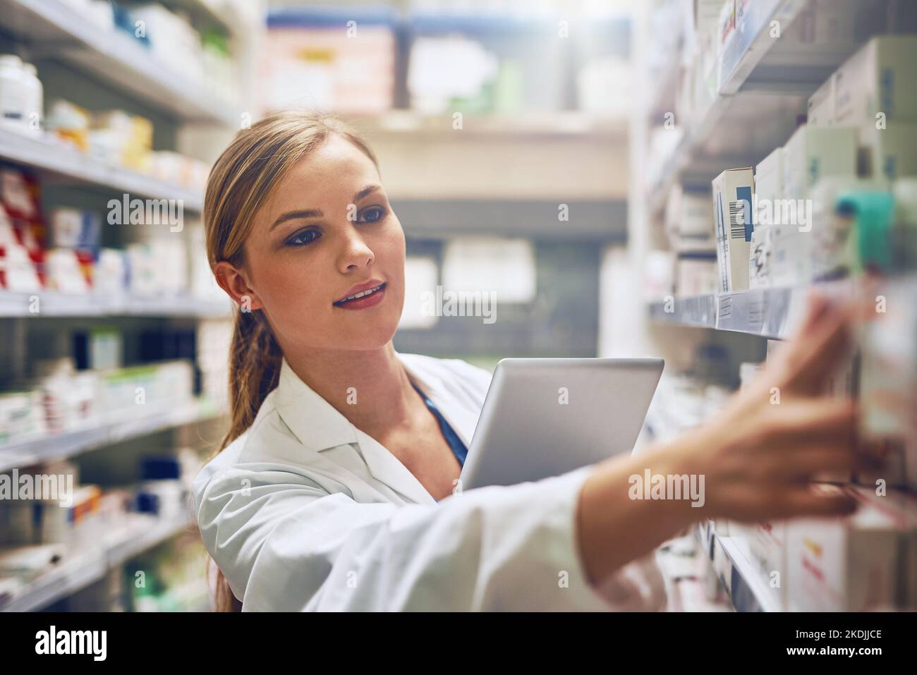 Verwendung von Online-Tools zur Auswahl der besten Medikamente. Eine Apothekerin, die ihre digitale Tablette verwendet, während sie auf einer Insel arbeitet. Stockfoto