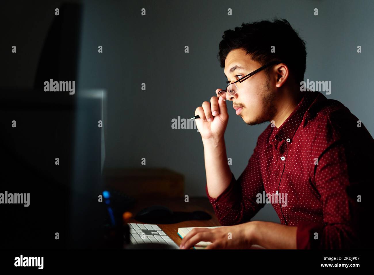 Ein junger Designer, der spät in der Nacht an seinem Computer arbeitet. Stockfoto