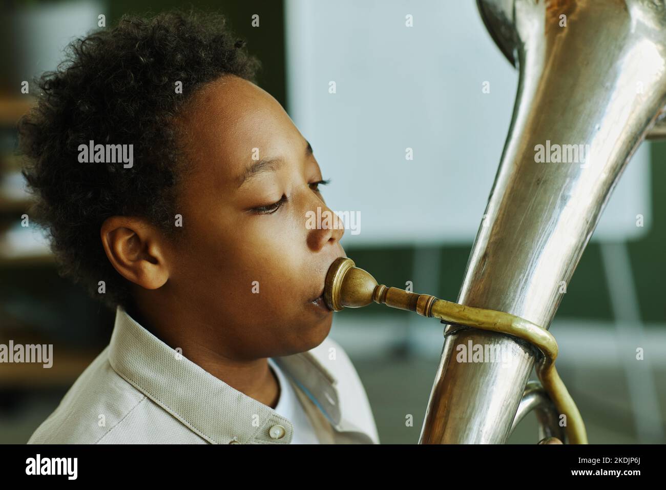 Nahaufnahme eines Jugendlichen afroamerikanischen Schuljungen, der während des individuellen Musikunterrichts mit dem Lehrer im Klassenzimmer Trompete bläst Stockfoto