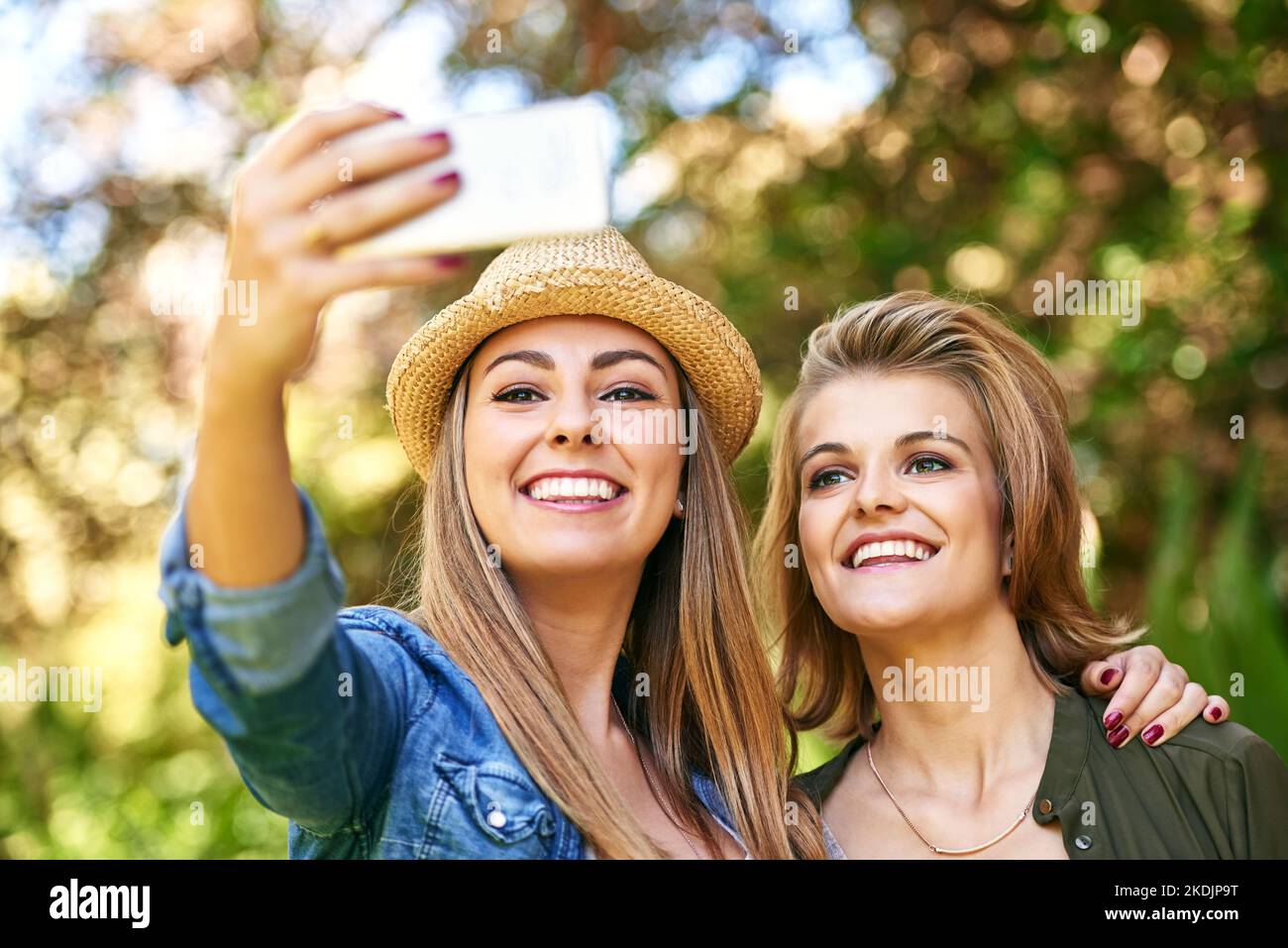 Zwei attraktive junge Frauen, die draußen Selfies machen. Stockfoto