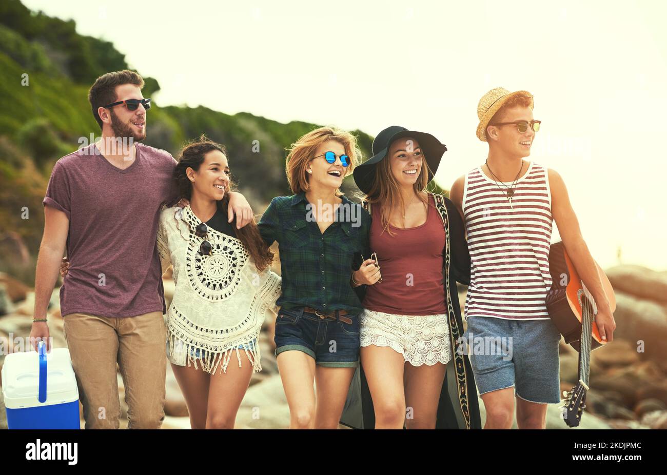 Sieht aus wie ein großer Strandtag. Eine Gruppe von Freunden, die an einem Sommertag am Strand spazieren. Stockfoto