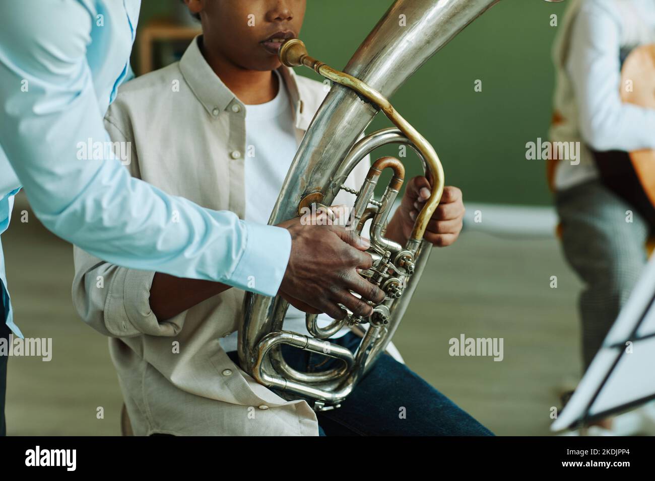 Nahaufnahme der Hand eines jungen afroamerikanischen Musiklehrers, der während des Unterrichts einem Schüler mit Blasinstrument hilft Stockfoto