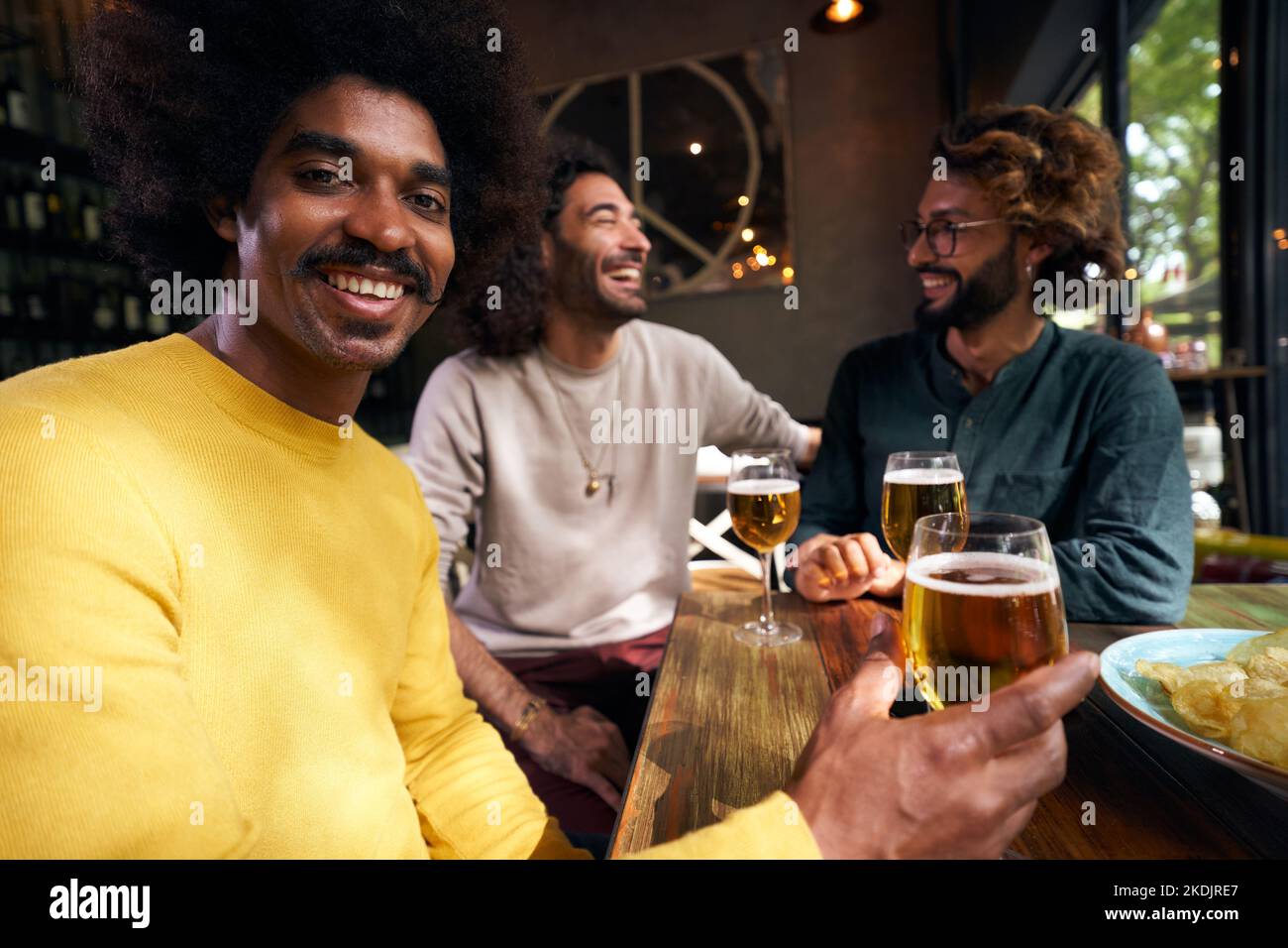 Fröhliches Porträt eines afroamerikanischen jungen Mannes mit einem Lächeln im Afro-Stil und Blick auf die Kamera. Stockfoto
