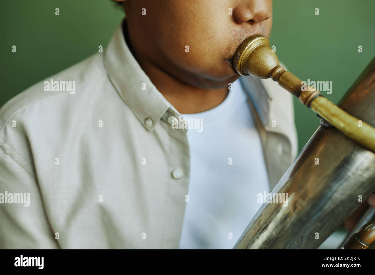 Nahaufnahme eines afroamerikanischen Schuljungen aus der Vorzeit in der Casualwear, der Trompete bläst, während einer Einzelstunde mit Musik auf grünem Hintergrund Stockfoto